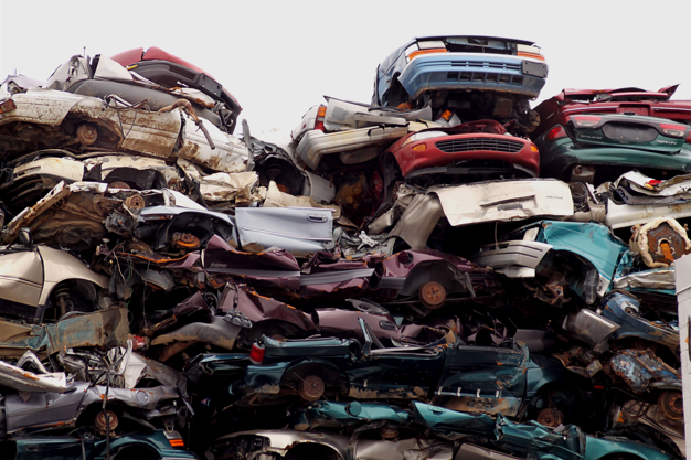 A pile of crushed scrap metal cars at an eco-friendly auto wrecker facility.